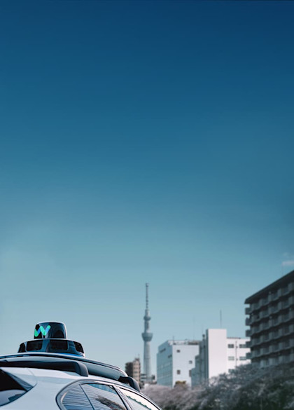 Waymo vehicle in front of Tokyo skyline