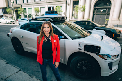 Lili posing in front of a Waymo autonomous vehicle in Los Angles.